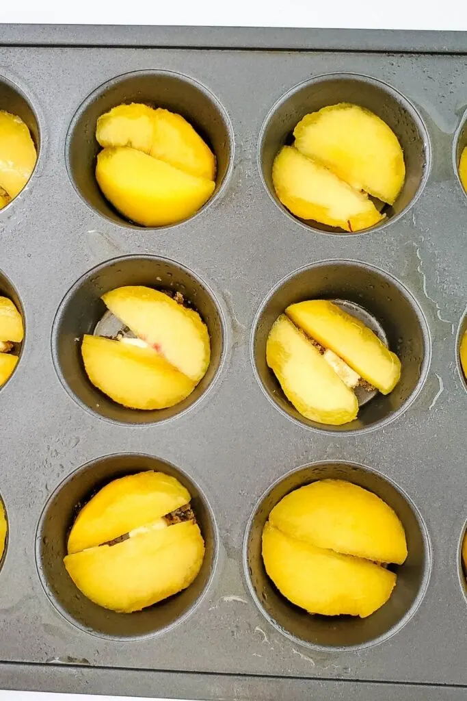 peaches in a muffin tin on top pf butter and sugar