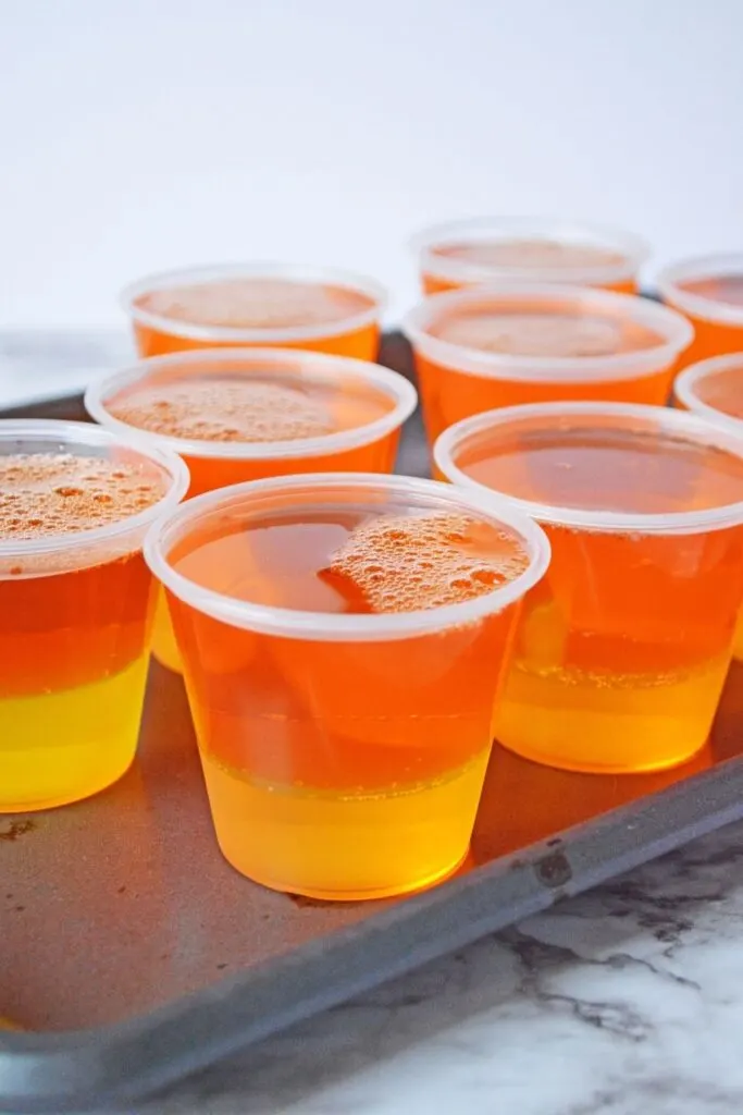 orange and pineapple jello in plastic cups