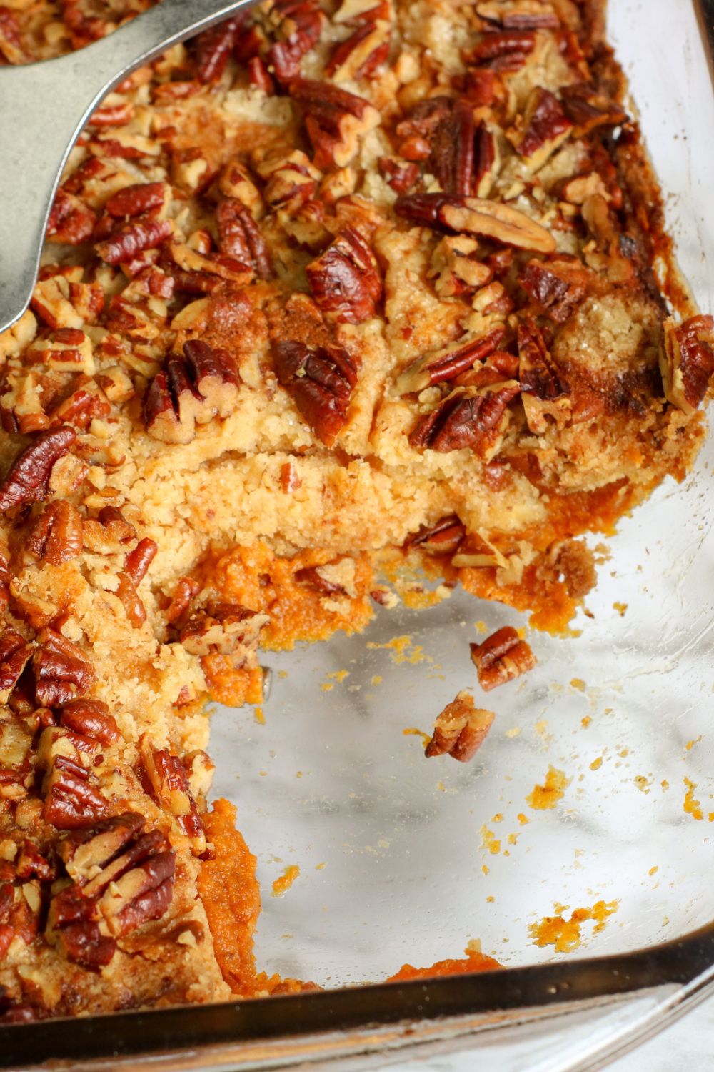 Baked pumpkin pecan cake in a baking dish with a piece taken out