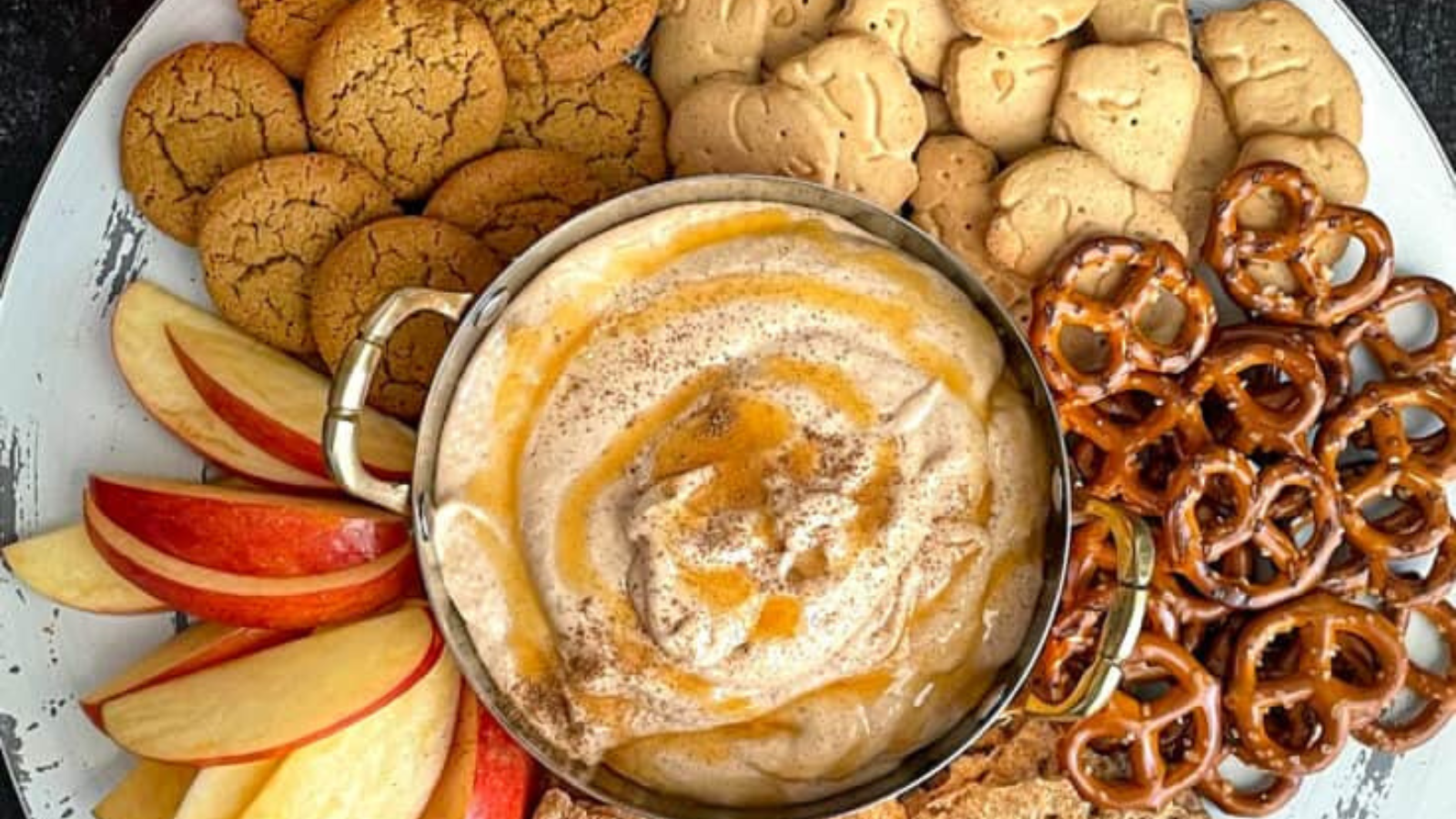A bowl of pumpkin pie dip with cookies and fruit.