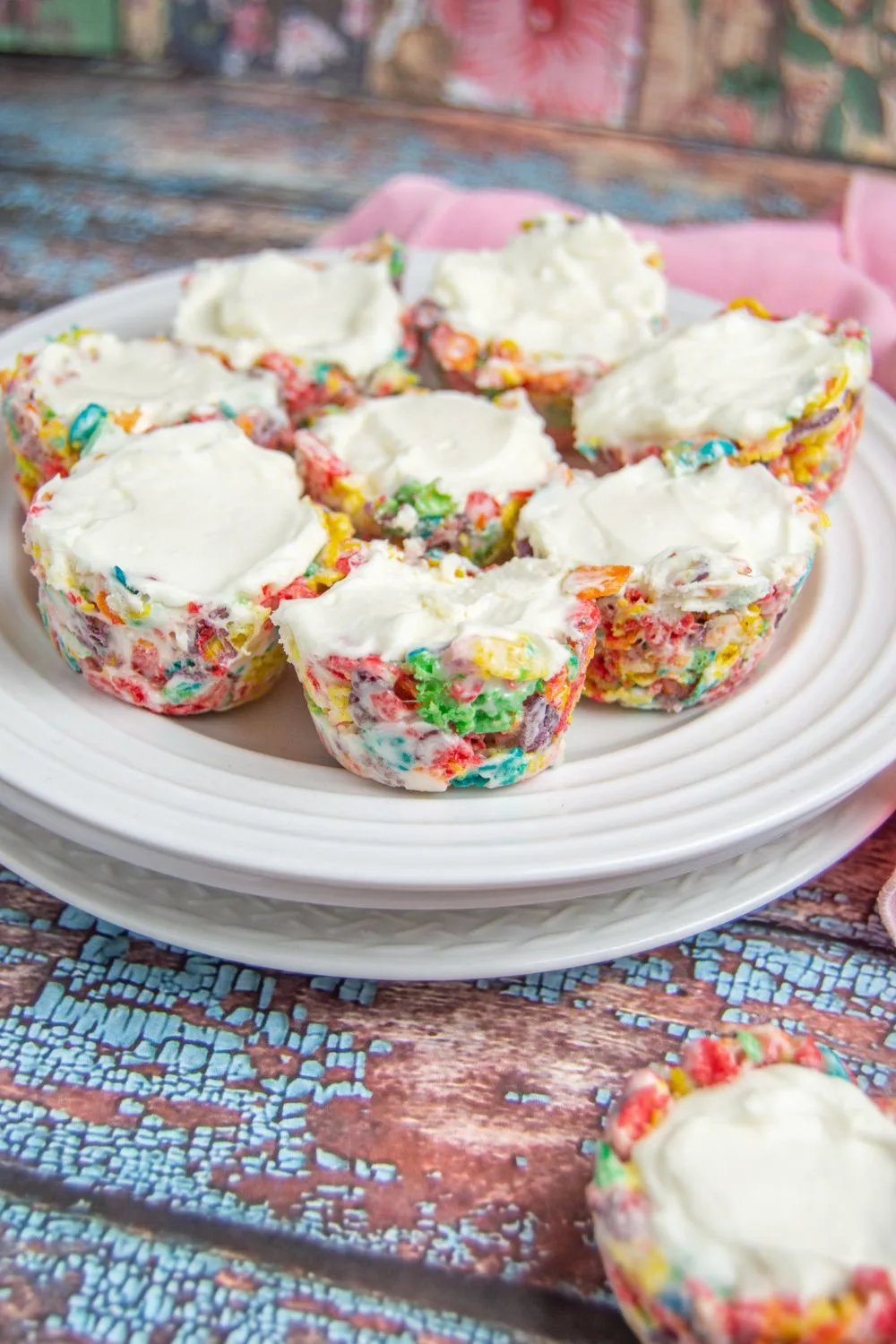 Fruity Pebbles Cheesecake Bites on a white plate with a blue worn wood background