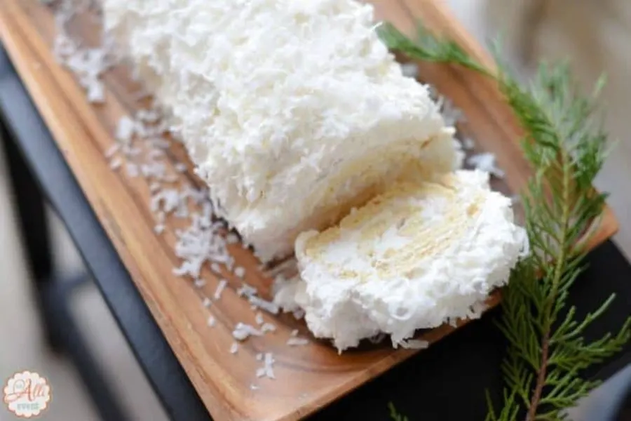 A coconut coated cake roll on a plate.