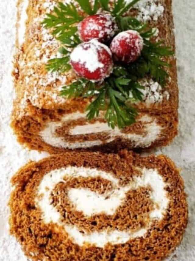 top view of sliced cake roll with leaves, cranberry and powdered sugar topping