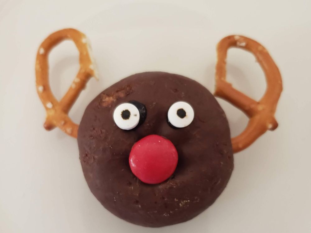 chocolate donut with pretzel antlers and eyeball sprinkles and red M&M for a nose