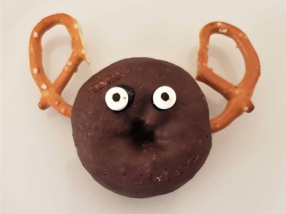 chocolate donut with pretzel antlers and eyeball sprinkles