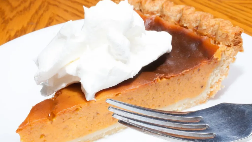 sweet potato bourbon pie with whipped cream on top on a plate