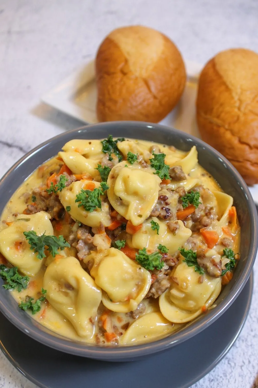kale sausage tortellini soup in a bowl with rolls