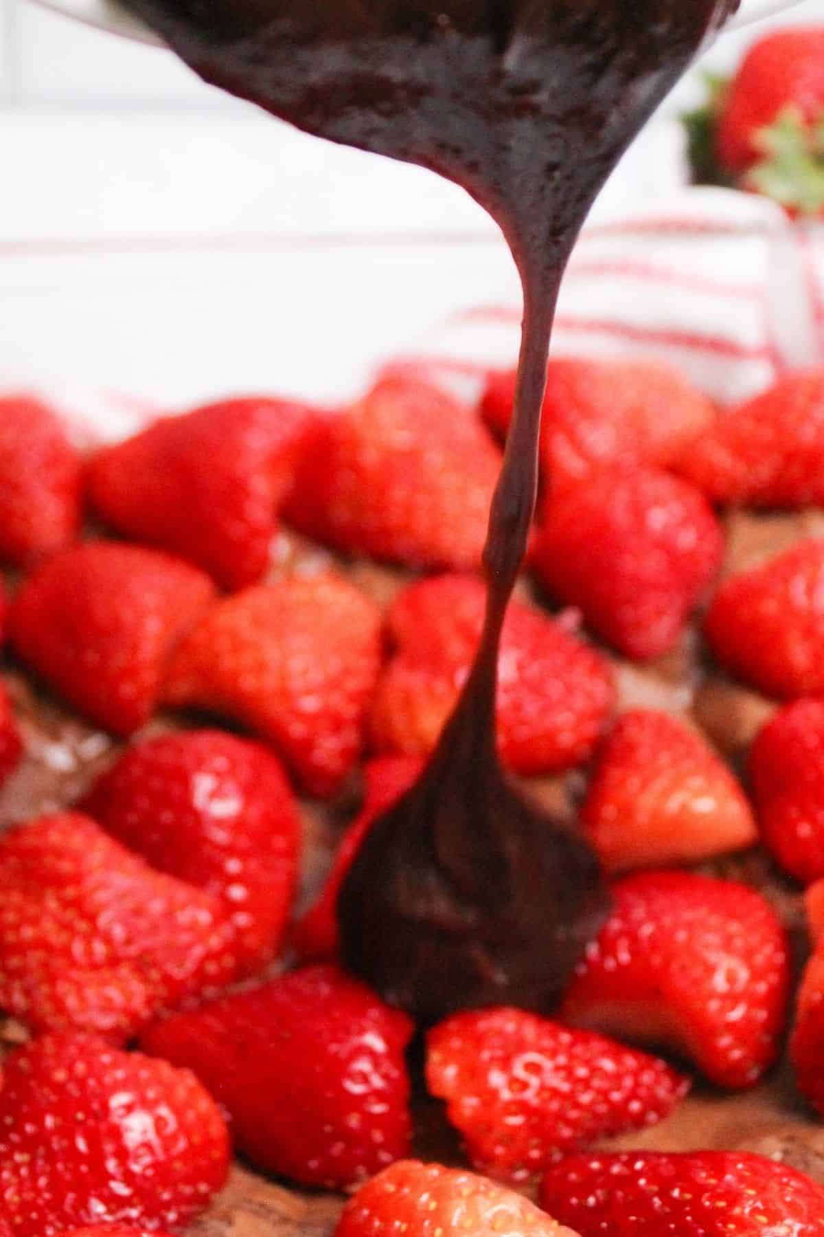 chocolate being poured onto brownies and strawberries