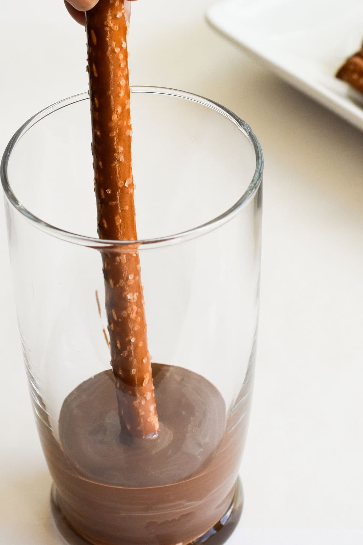 Dipping pretzel rods into melted chocolate.