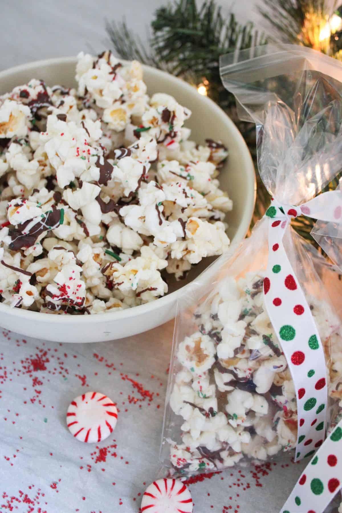 A bowl of xmas popcorn next to a sealed treat bag of the same popcorn.