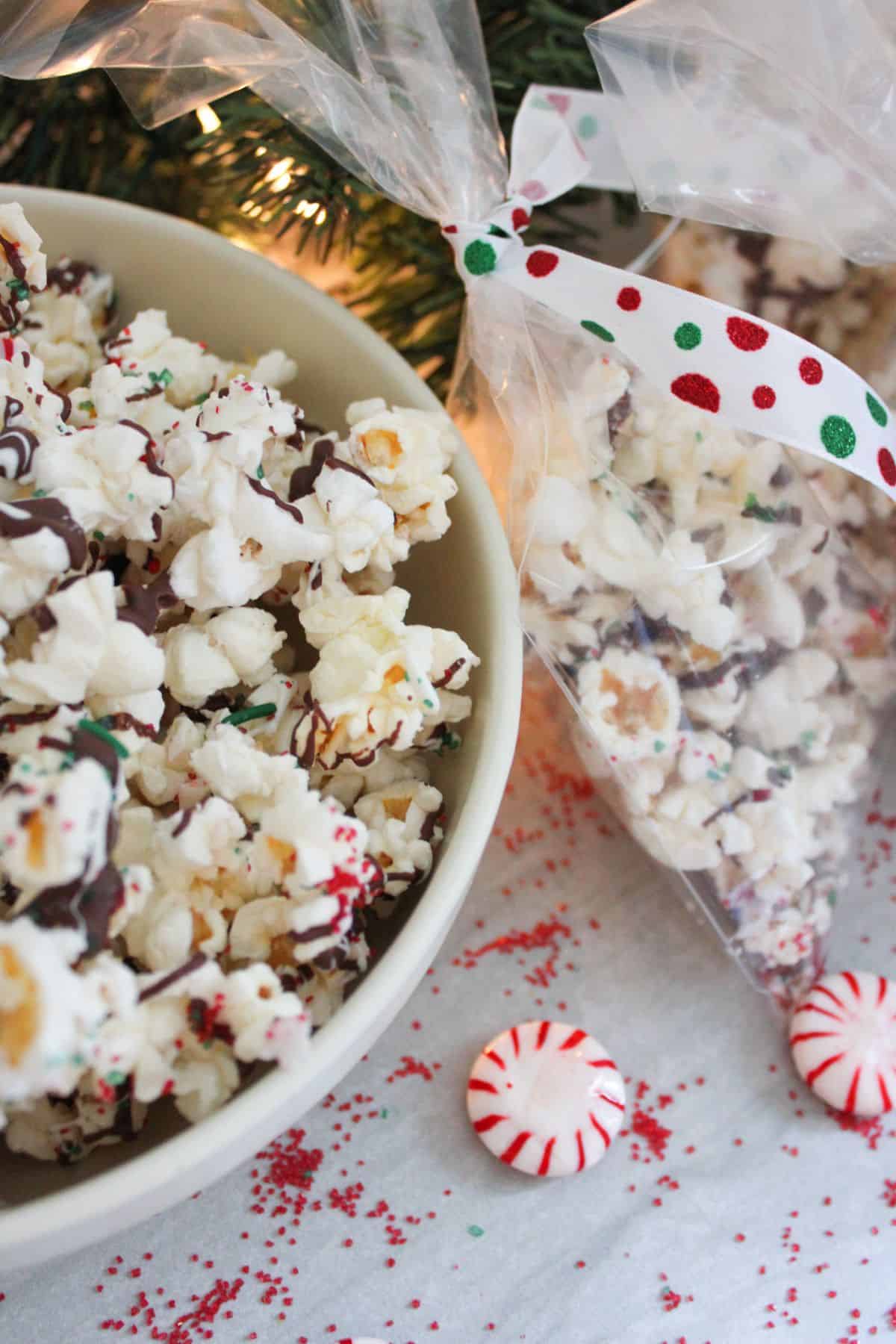 A bowl of xmas popcorn next to a sealed treat bag of the same popcorn.